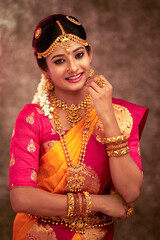 Obraz premium Beautiful smiling Indian bride with jewelry in studio shot.