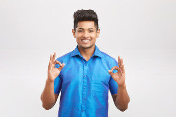 Cheerful handsome south Indian man showing ok sign on white.