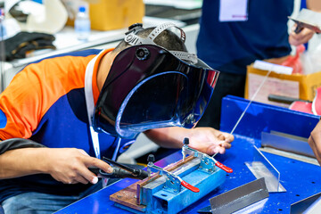 Fototapeta na wymiar worker or tig welder wearing a mask for protect light and smoke during welding metal assembly part or workpiece on table