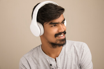Young man listening music through headphones in studio shot.