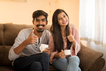 Cheerful young friends chatting on sofa at home.