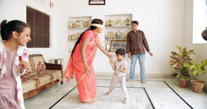 Slow-motion shot of a family playing hide and seek extreme blindfolded in their home as they take turns to catch each other enjoy happiness share playful having fun joyous laughing smiling 