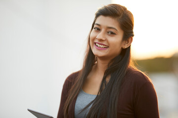 Fototapeta premium Cheerful attractive Indian young women using digital tablet at outdoor background.
