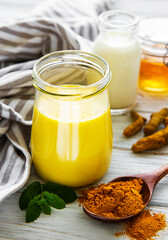 Yellow turmeric latte drink. Golden milk with cinnamon, turmeric, ginger  and honey over white...