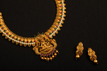 Traditional Indian Gold Necklace With Earrings on black background.