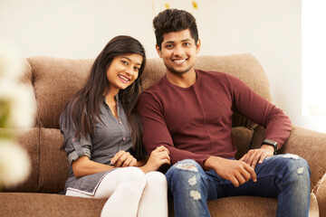 Young beautiful couple chatting on sofa at home