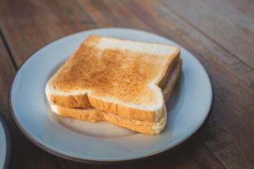 Fototapeta na wymiar Toasts bread on a white dish on a wooden floor