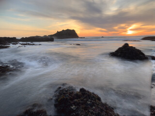 Obraz premium sunset over the sea with rocks and surf