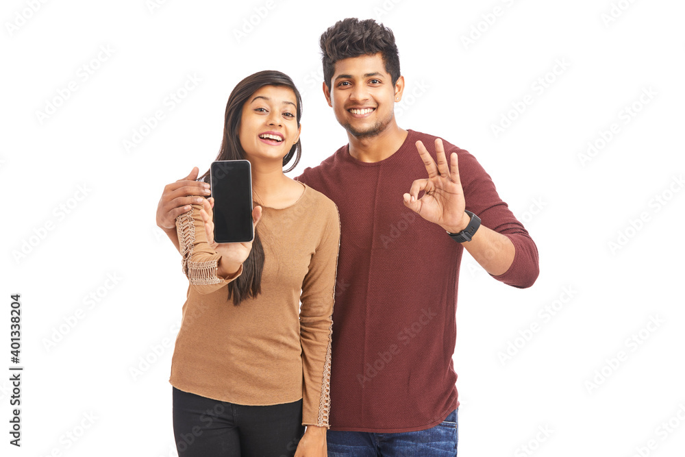 Wall mural Beautiful happy young couple holding smart phone on white.