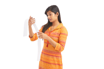 Shocked young woman looking at a store receipt on white.