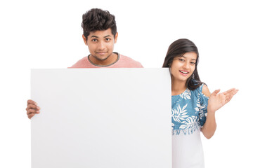 Cheerful young couple holding billboard on white background.