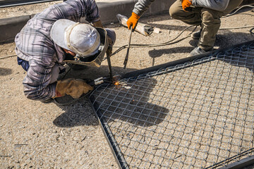 Welder welding a fence in the street. Electric welder makes the fence.