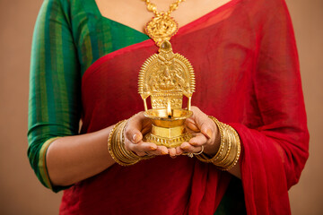 Hindu Indian young women holding Deepam in hands studio shot. ( Kamatchi vilakku )