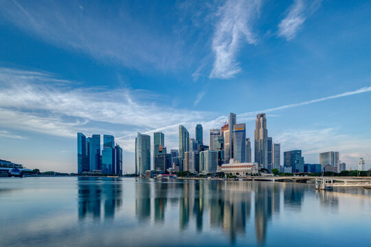 Wide panorama image of Singapore skyscrapers illuminated by morning sunlight early in the morning.