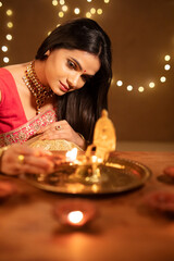 Beautiful Hindu Indian young women lightening Diya on Diwali day.
