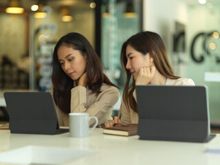 Two businesswomen consulting on their project, talking to each other in meeting room