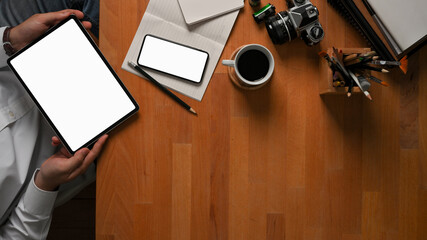 Businessman using digital tablet on wooden worktable with smartphone, supplies and copy space