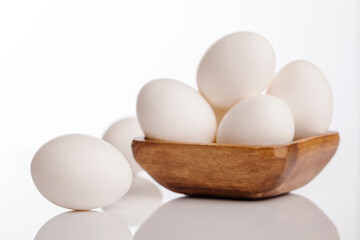 Wooden cup of white eggs on white background.