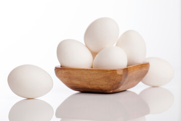 Wooden cup of white eggs on white background.