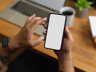 Close up view of male hands using smartphone while sitting at workplace