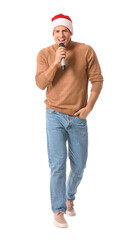 Young man with microphone singing Christmas song on white background