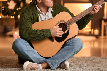 Young man playing guitar at home on Christmas eve