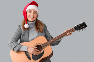 Fototapeta premium Mature woman playing guitar on grey background
