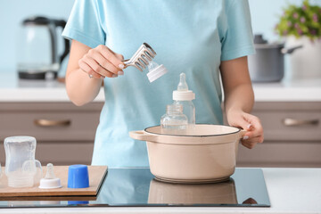 Woman cleaning baby bottle at home