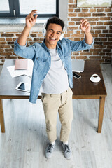 high angle view of happy african american man standing near desk with gadgets.