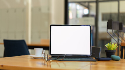 Glass partition office room with digital tablet and supplies on wooden table