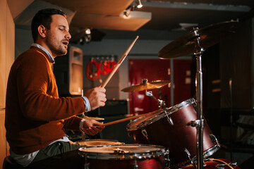 Drummer enjoy playing drums in studio, side view.