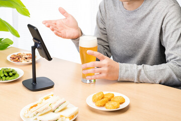 スマートフォンでリモート飲み会をする男性