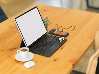 Side view of workspace with tablet, eyeglasses, accessories and coffee cup