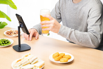 スマートフォンでリモート飲み会をする男性