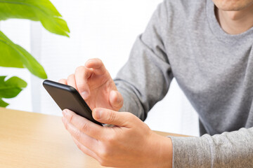 てスマートフォンを操作する男性