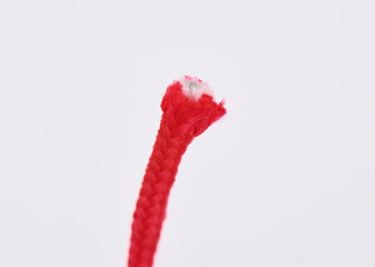 Ragged edge of torn red paracord on white background