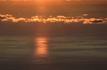 Clouds in the Golden light of the rising sun on the background of the sea surface