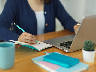 Close up view of female university student writing on blank notebook