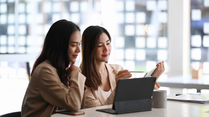 Shot of two businesswoman using tablet and discussing strategy for company growth.