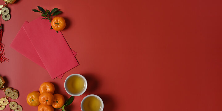 Flat lay accessories Chinese new year festival decorations with orange, red packet and copy space on red background.
