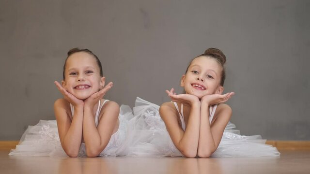 Adorable little sisters talking, relaxing after exercising at ballet school. Friendship, childhood, family concept.