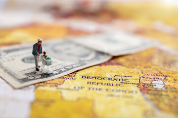 Miniatrue people: Shoppers with shopping cart standing on the  money. and world map. Shopping  and business concept.