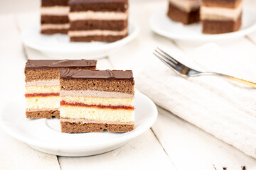 Wedding cake with chocolate topping, cocoa and biscuit dough, chocolate cream and strawberry jam.  Served on white wooden table in retro style. Delicious dessert especially with coffee.
