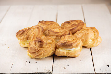 Profiterole cakes on white wooden table. Creamy filling and crunchy dough on the bottom and top of the cake. In Slovakia traditional wedding cake.