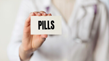 Doctor holding a card with text word PILLS, medical concept.