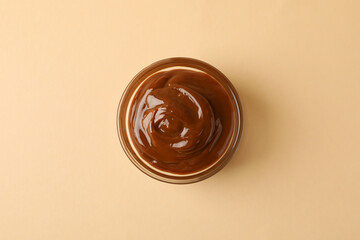 Glass bowl with caramel condensed milk on beige background