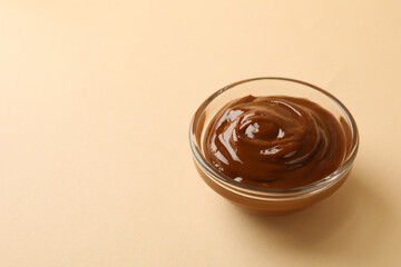 Glass bowl with caramel condensed milk on beige background