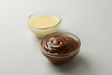 Bowls with condensed milk on gray background