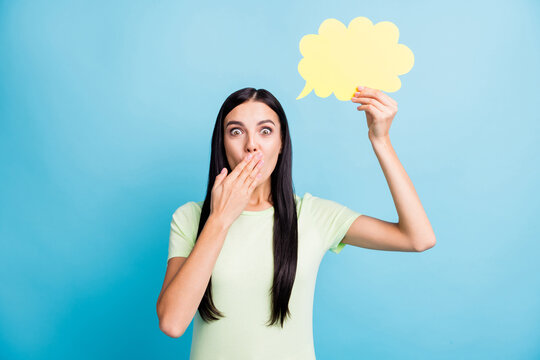 Photo portrait of girl suddenly realizing something covering mouth with hand holding yellow thought bubble isolated on pastel blue colored background