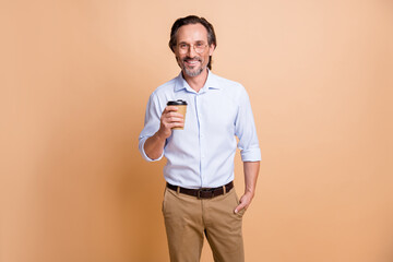 Photo of positive guy hold takeaway coffee cup hand pocket look camera wear specs shirt isolated beige color background